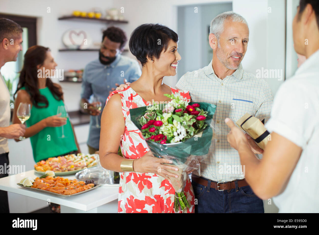 Couple bringing flowers to party Stock Photo