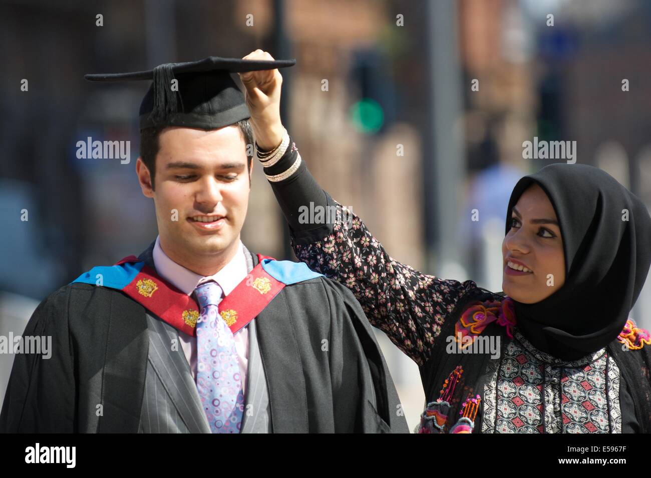 Manchester,  UK.  24th July, 2014. Mohammed Adel has his mortar board adjusted before entering The Bridgewater Hall to receive his B.Sc. in Business Information Technology, which he gained with First Class Honours. Graduation (Manchester Metropolitan University) Manchester, UK Credit:  John Fryer/Alamy Live News Stock Photo