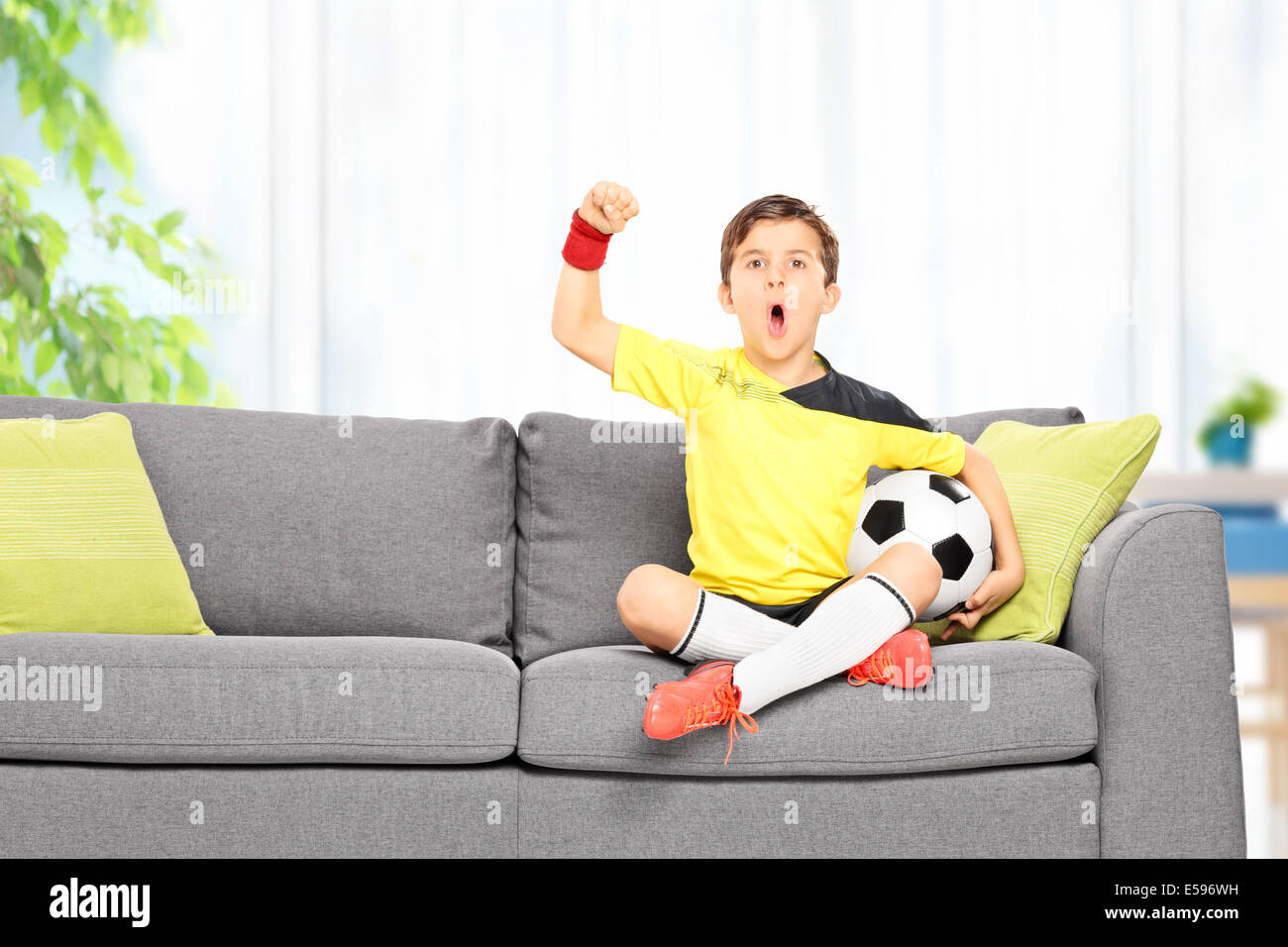 Little boy watching a football match on a sofa at home Stock Photo - Alamy