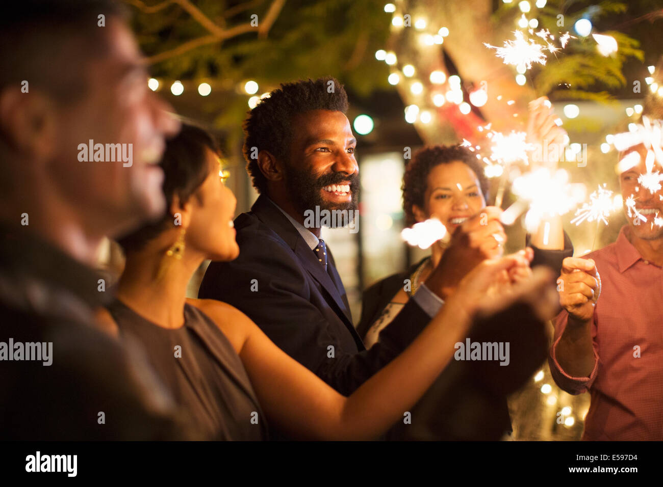 Friends playing with sparklers at party Stock Photo