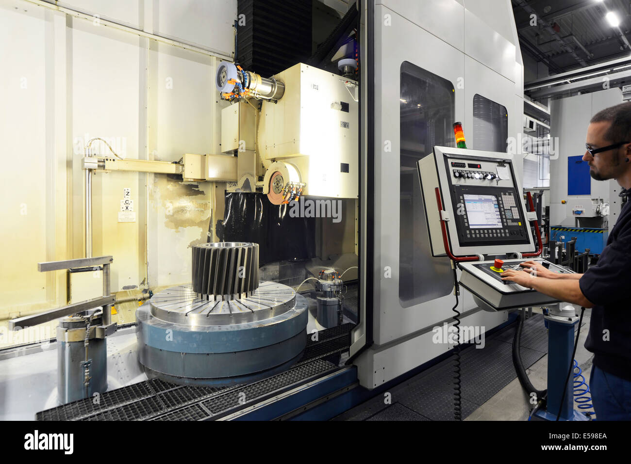 Germany, Saxony, man working at CNC machine at production hall Stock Photo