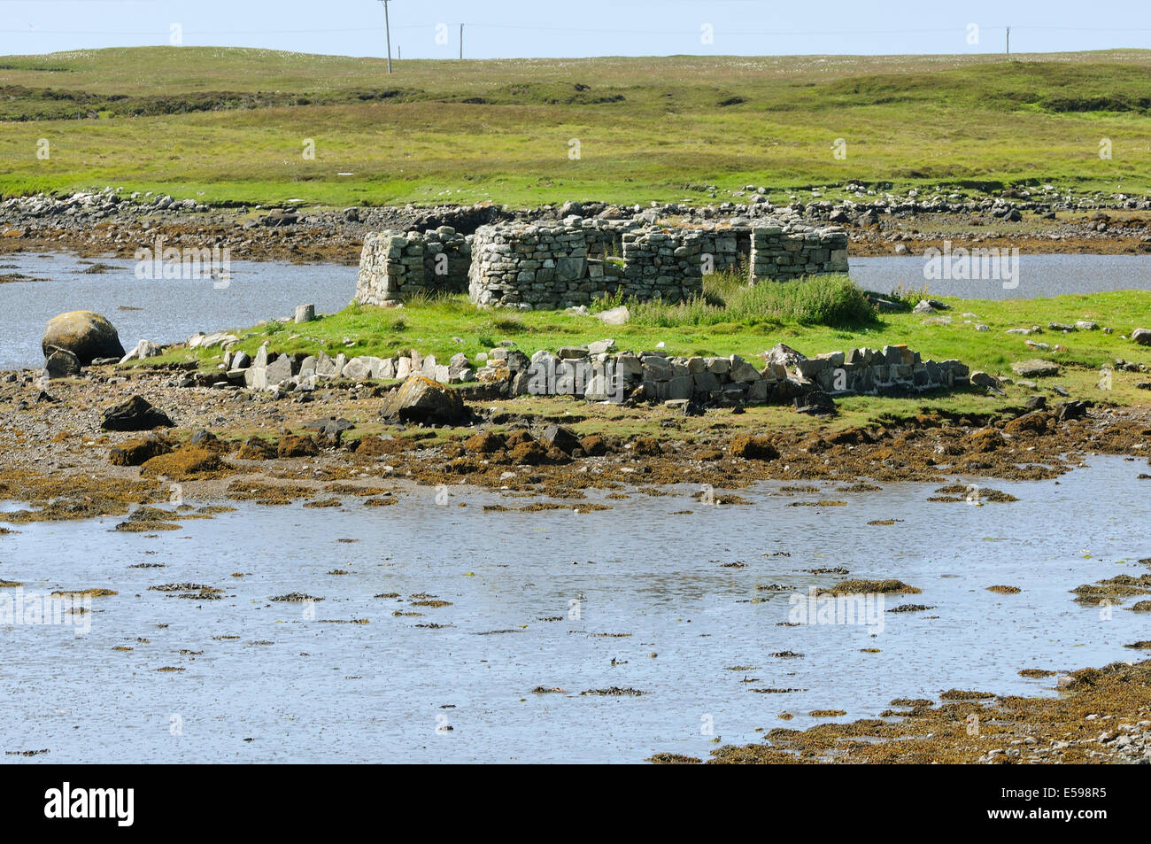 Ruined building on island in muddy sea loch, Benbecula Stock Photo