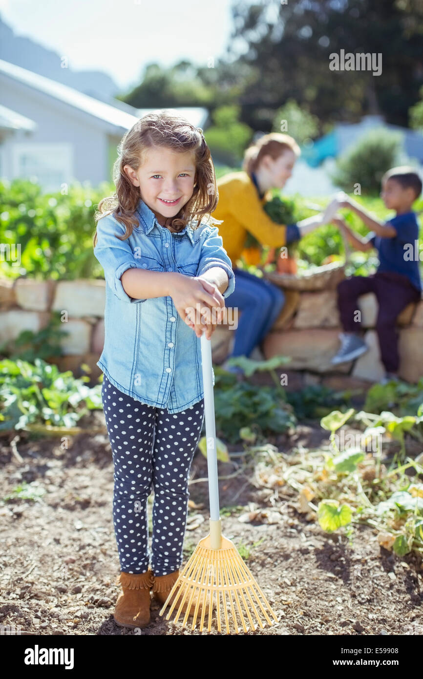 Girl holding rake in garden Stock Photo - Alamy