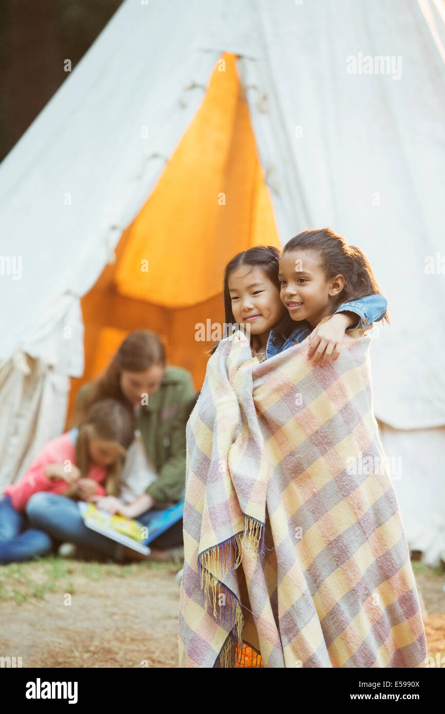 Girls wrapped in blanket at campsite Stock Photo Alamy