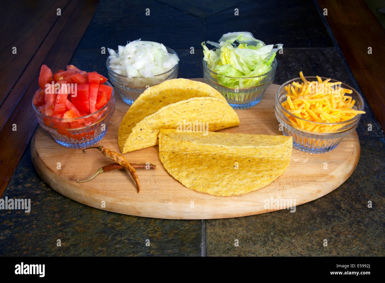 Assortment of taco condiments tomatoes, onions, lettuce and cheddar