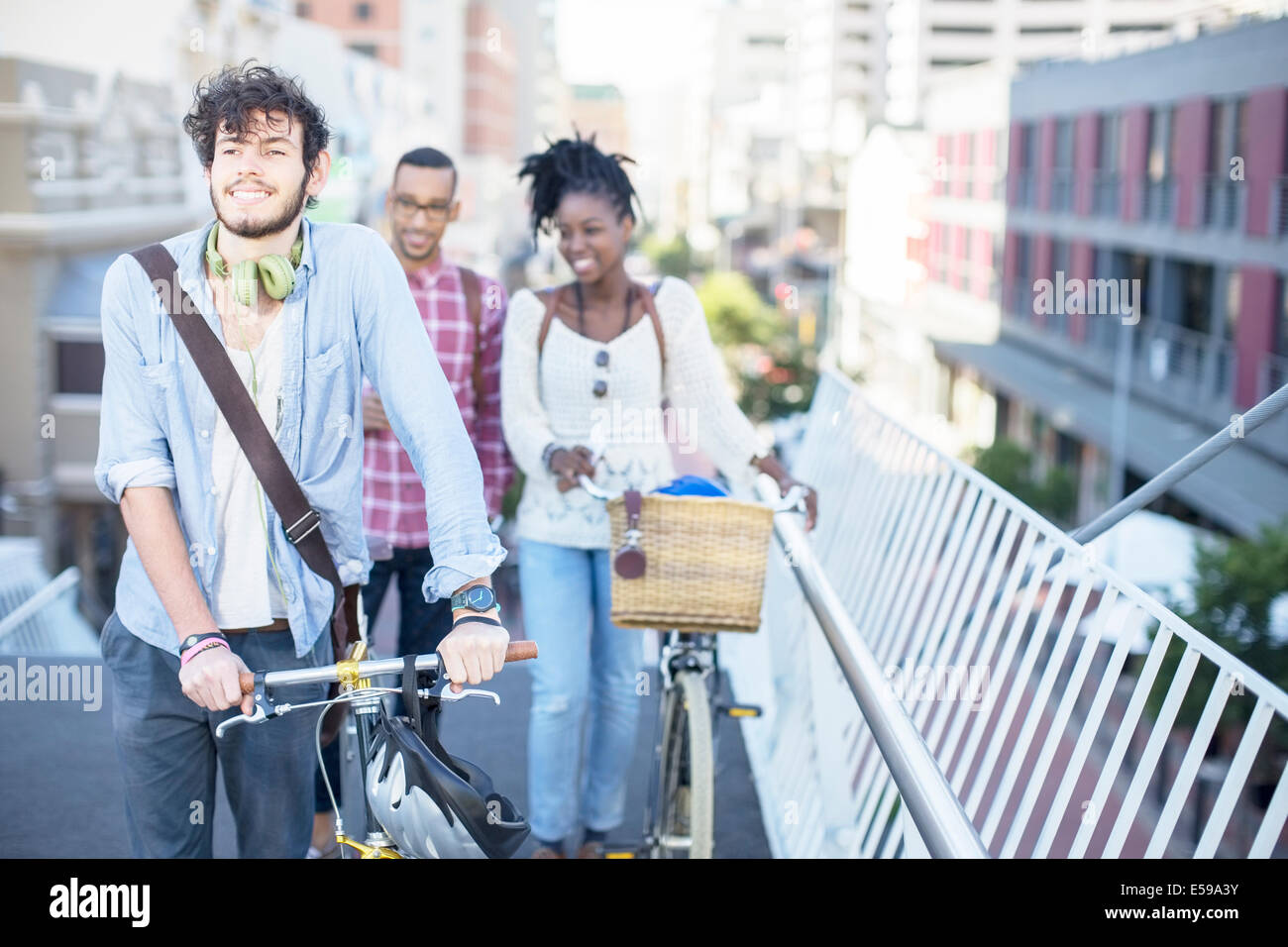 Friends pushing bicycles on city street Stock Photo