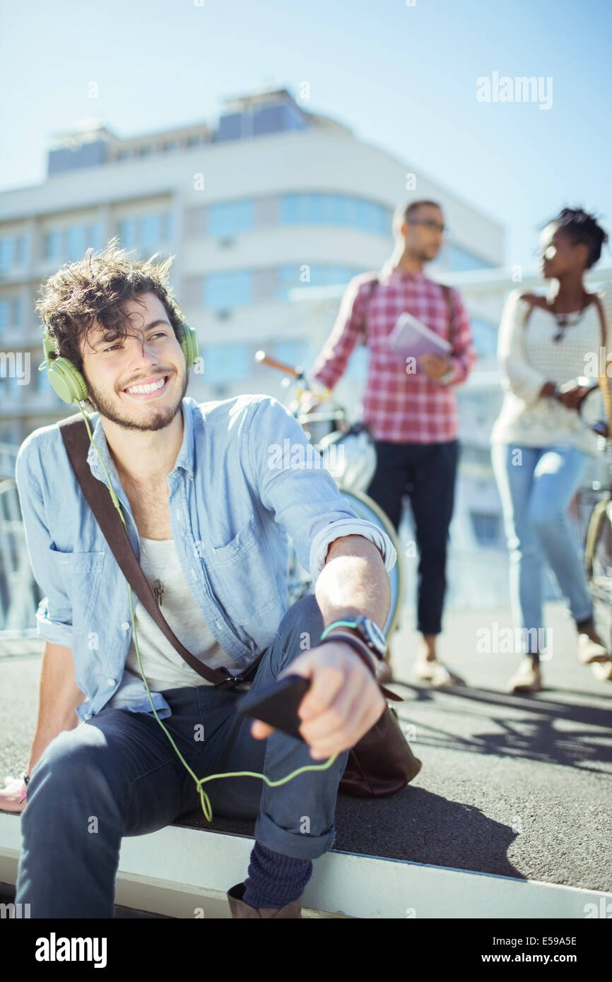 Man listening to mp3 player on city street Stock Photo