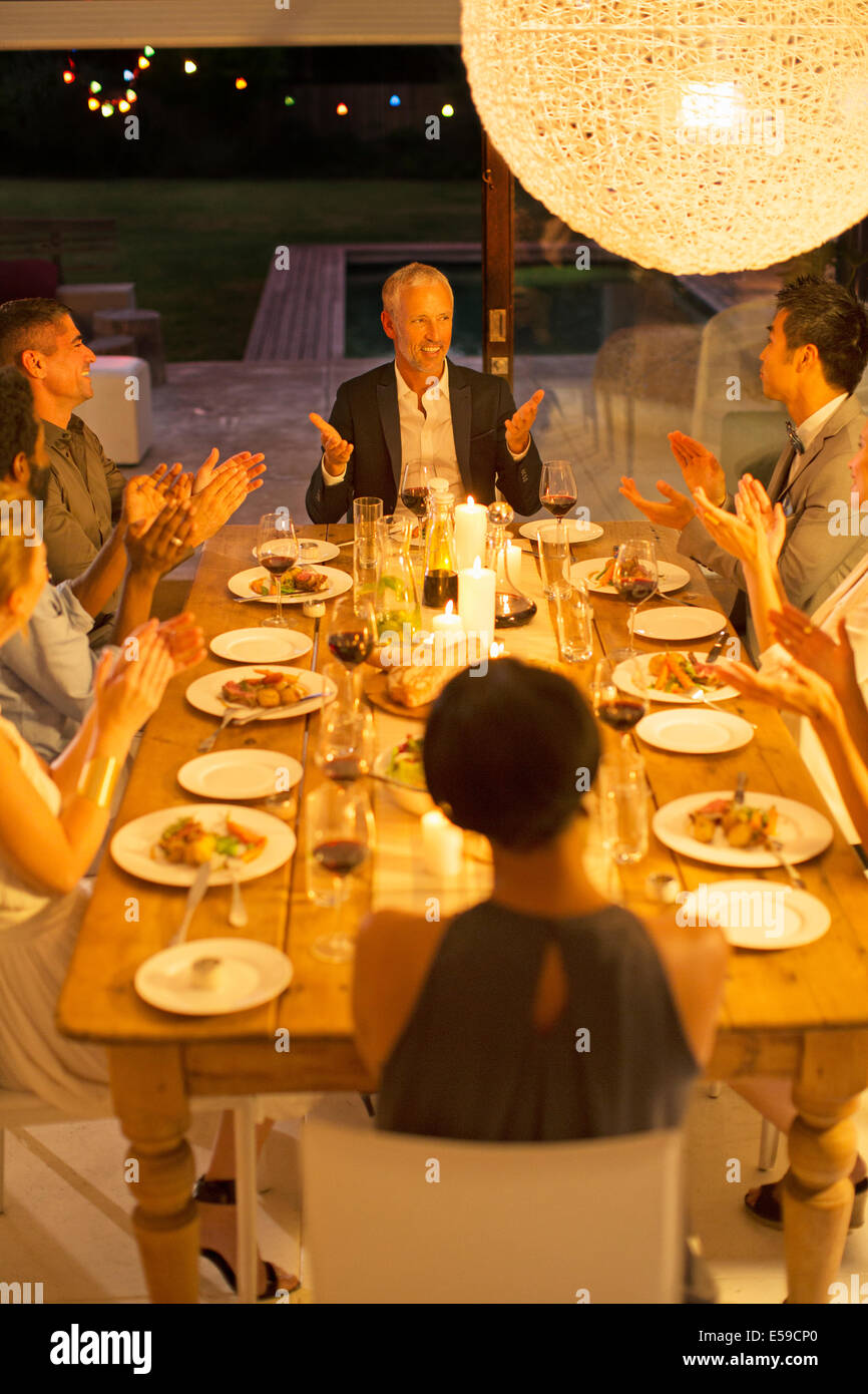 Friends applauding man at dinner party Stock Photo