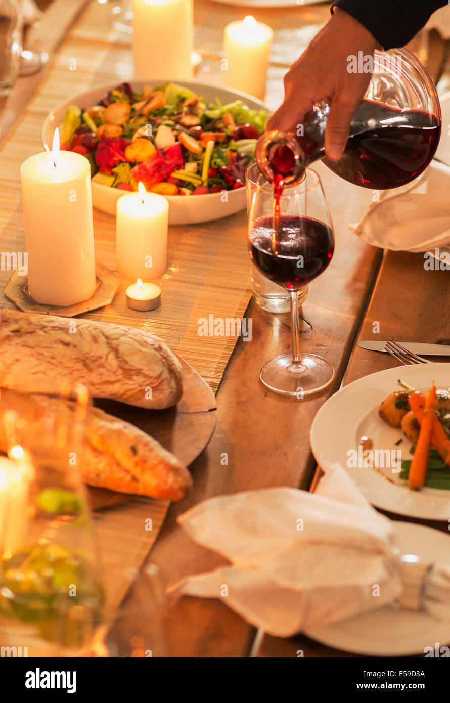 Woman pouring wine at dinner party Stock Photo
