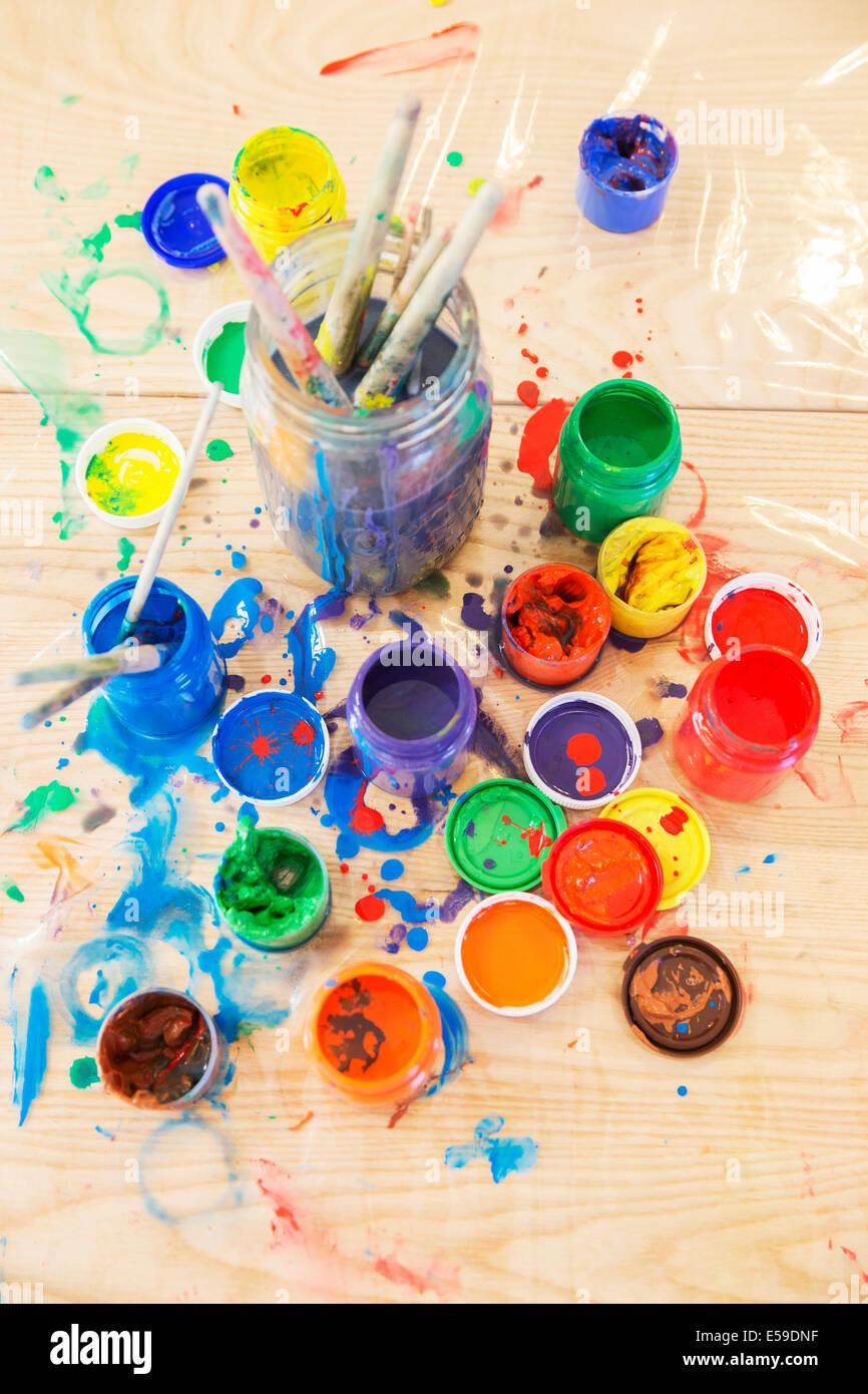 Jars of paint and paintbrushes on wooden table Stock Photo