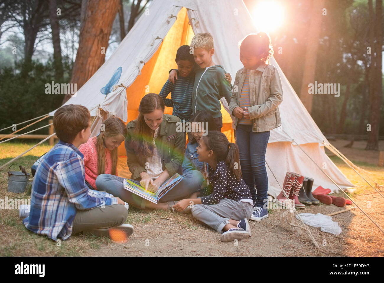 Teacher and students reading at campsite Stock Photo