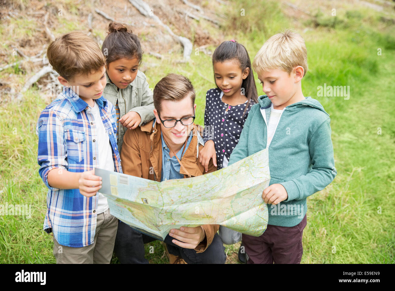 Students and teacher reading map outdoors Stock Photo