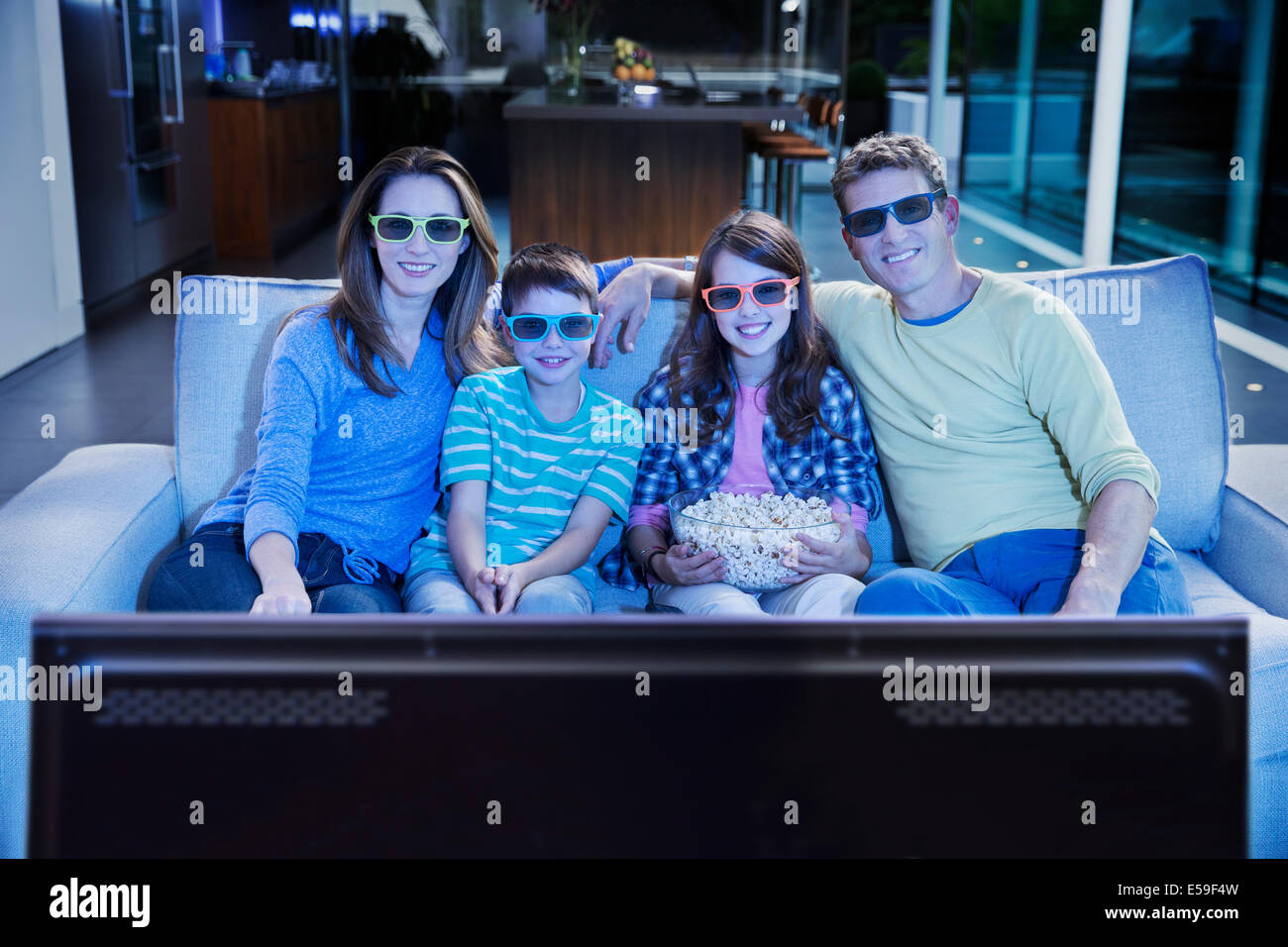 Family watching 3D television in living room Stock Photo