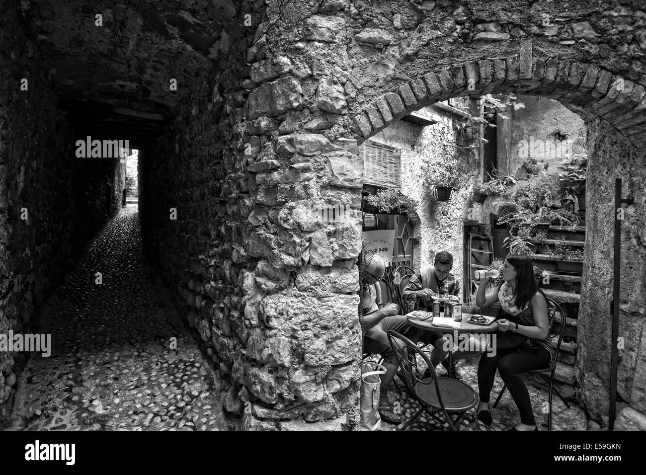 A family eat alfresco off the cobbled streets of Malcesine, Lake Garda, Italy Stock Photo