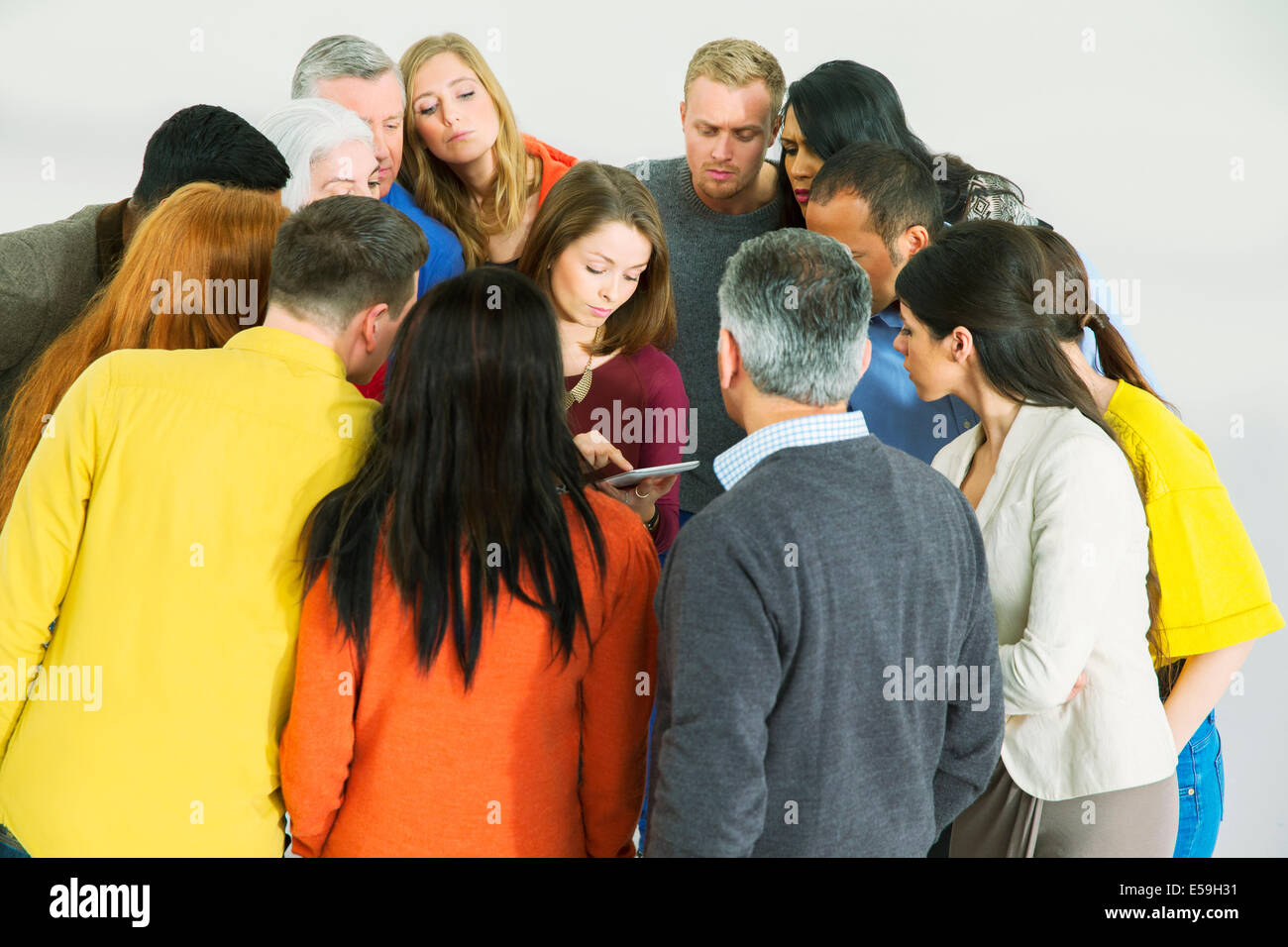 Business people huddled around businesswoman with laptop Stock Photo