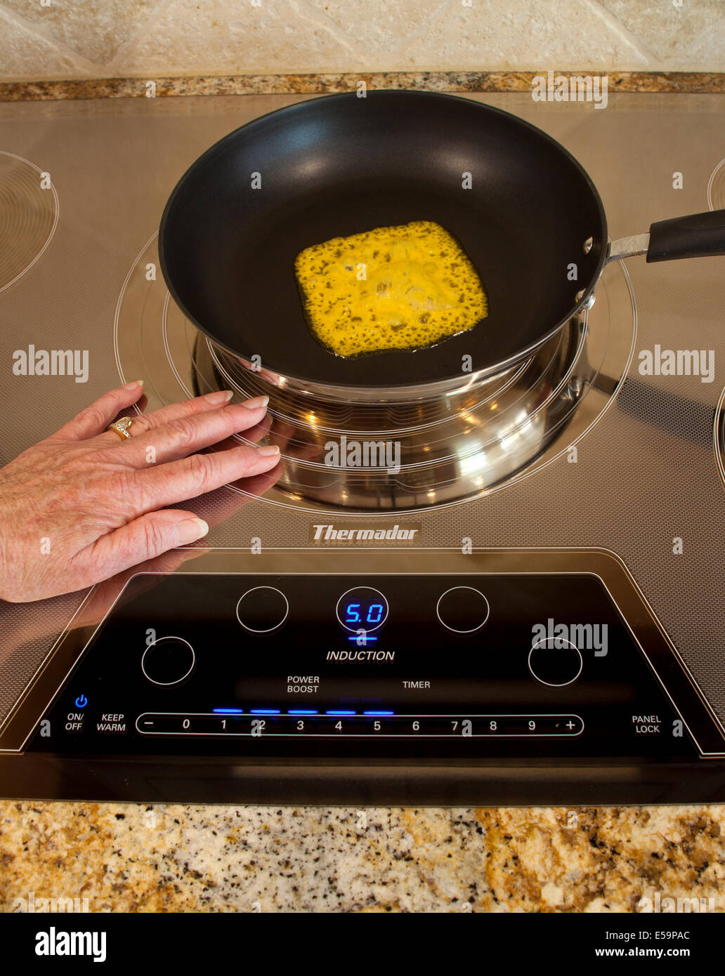 Magnetic energy of touching touch energy saving Thermador Induction cooktop with melting cheese Series of 4 images.  MR  © Myrleen Pearson Stock Photo