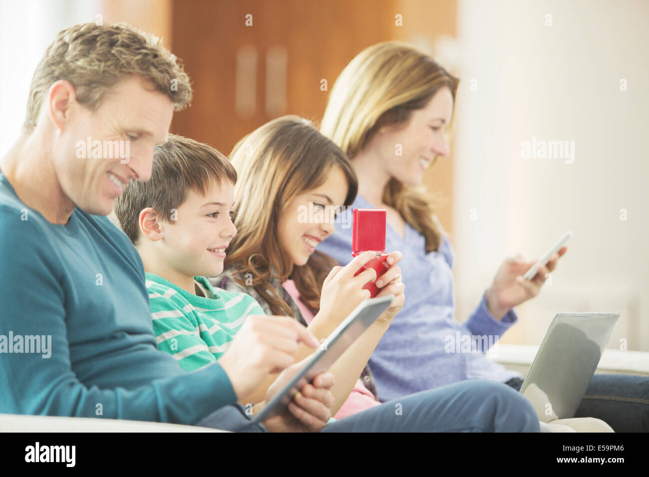 Family using technology on sofa Stock Photo