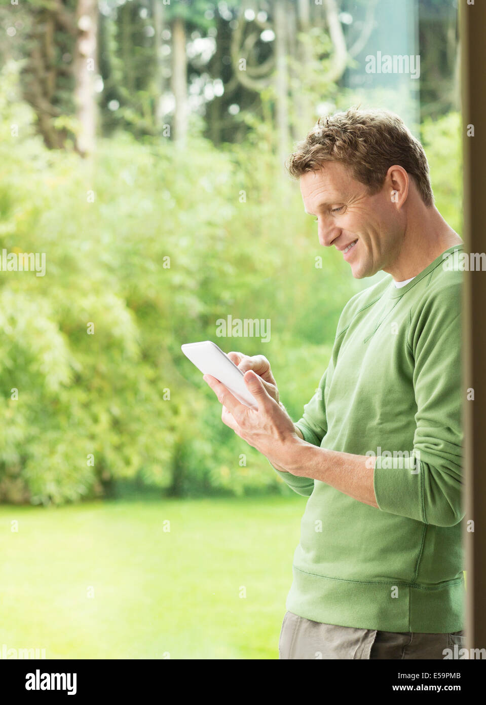 Man using digital tablet by window Stock Photo