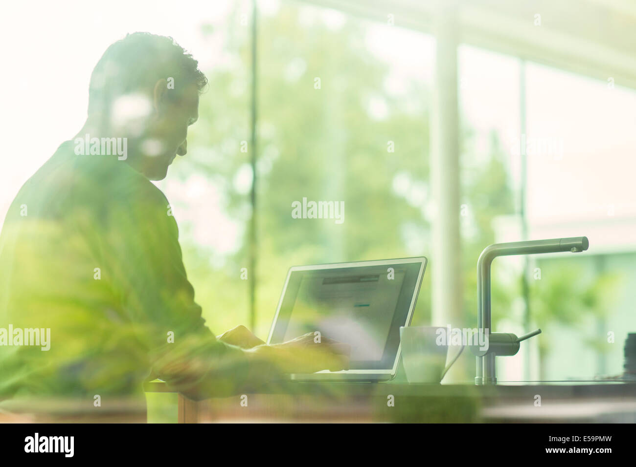 Man using laptop viewed through window Stock Photo