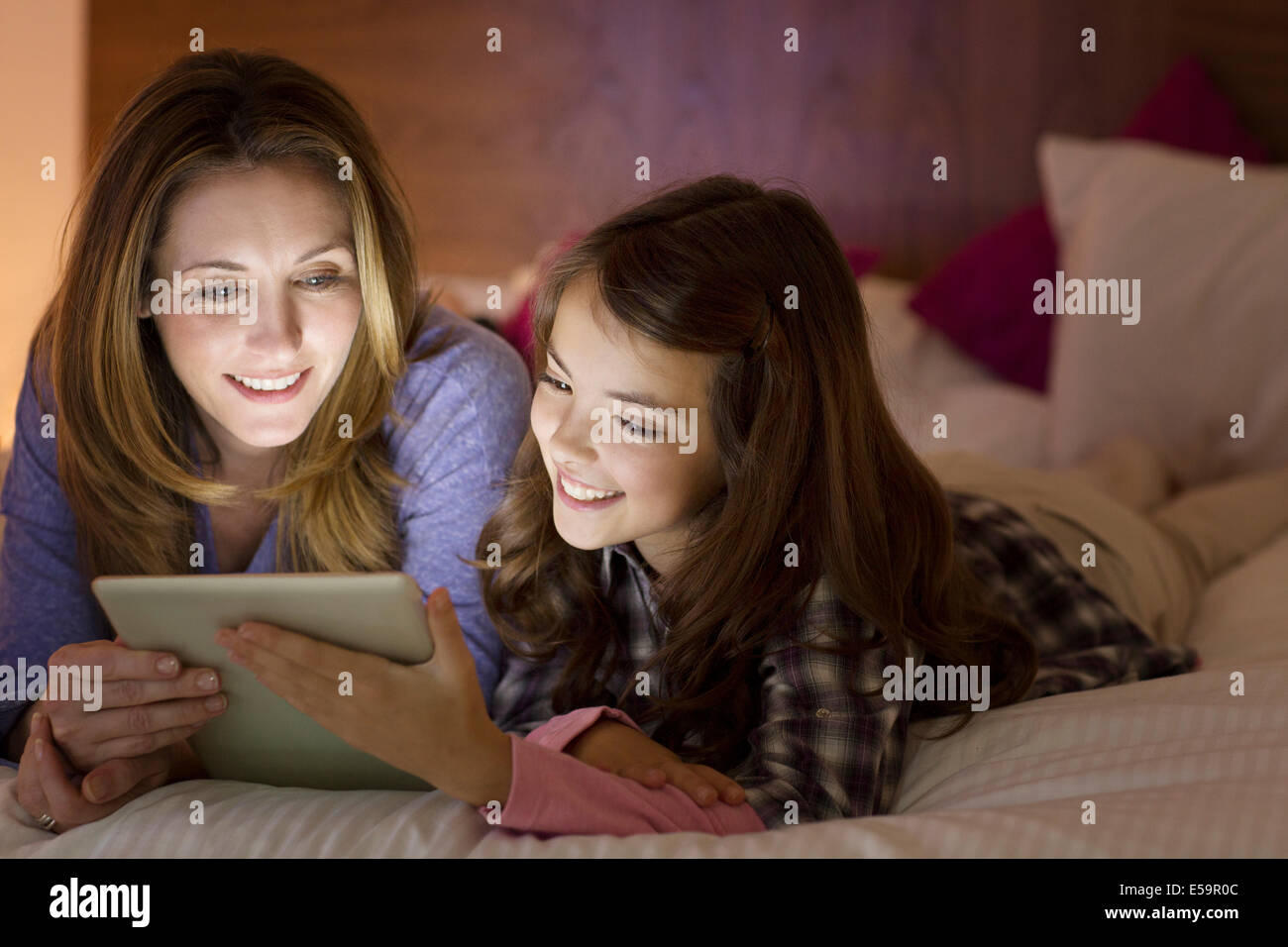 Mother and daughter using digital tablet on bed Stock Photo