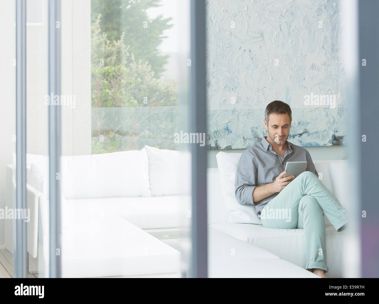 Man using digital tablet on sofa Stock Photo