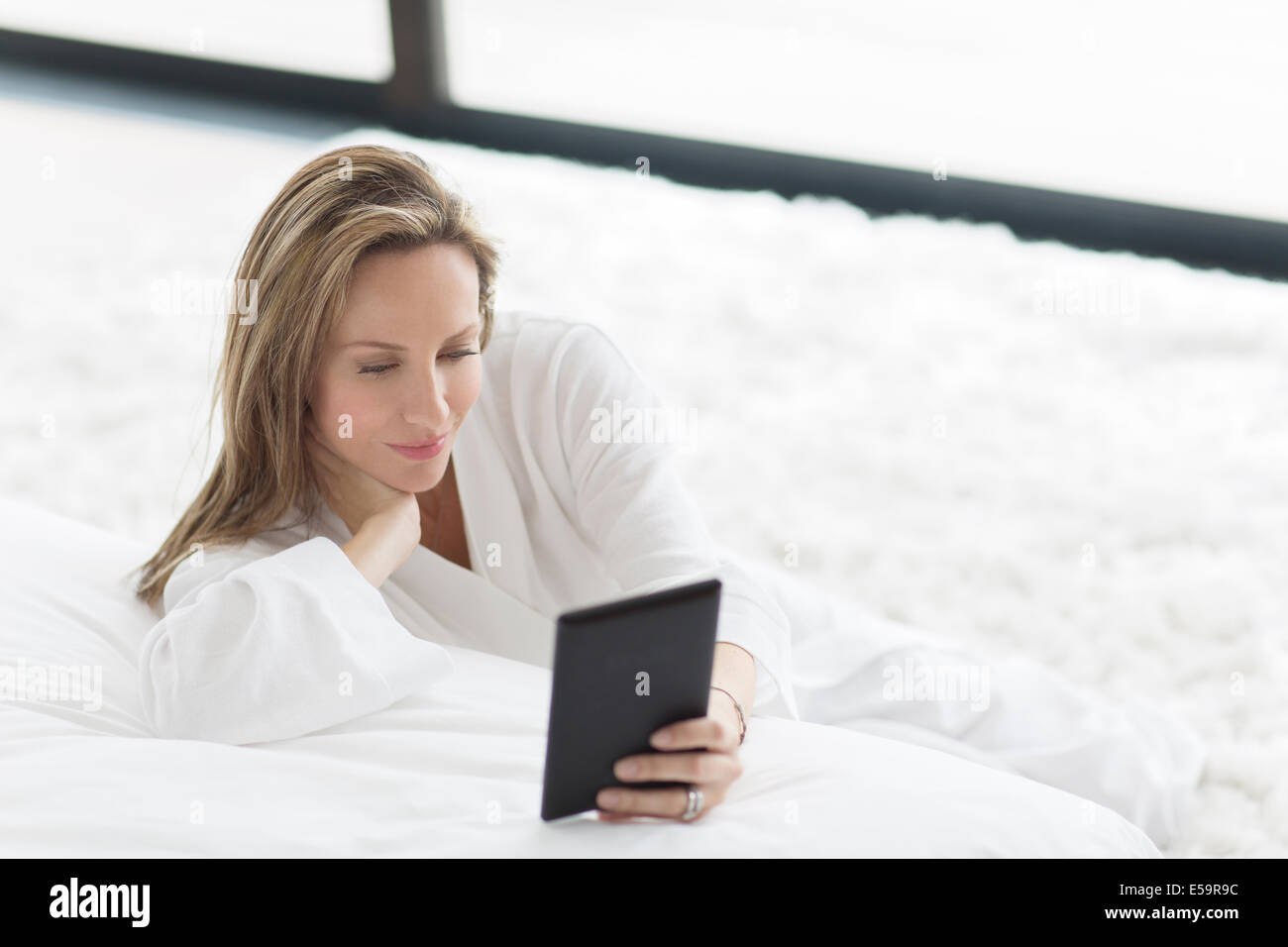 Woman in bathrobe using digital tablet in bedroom Stock Photo