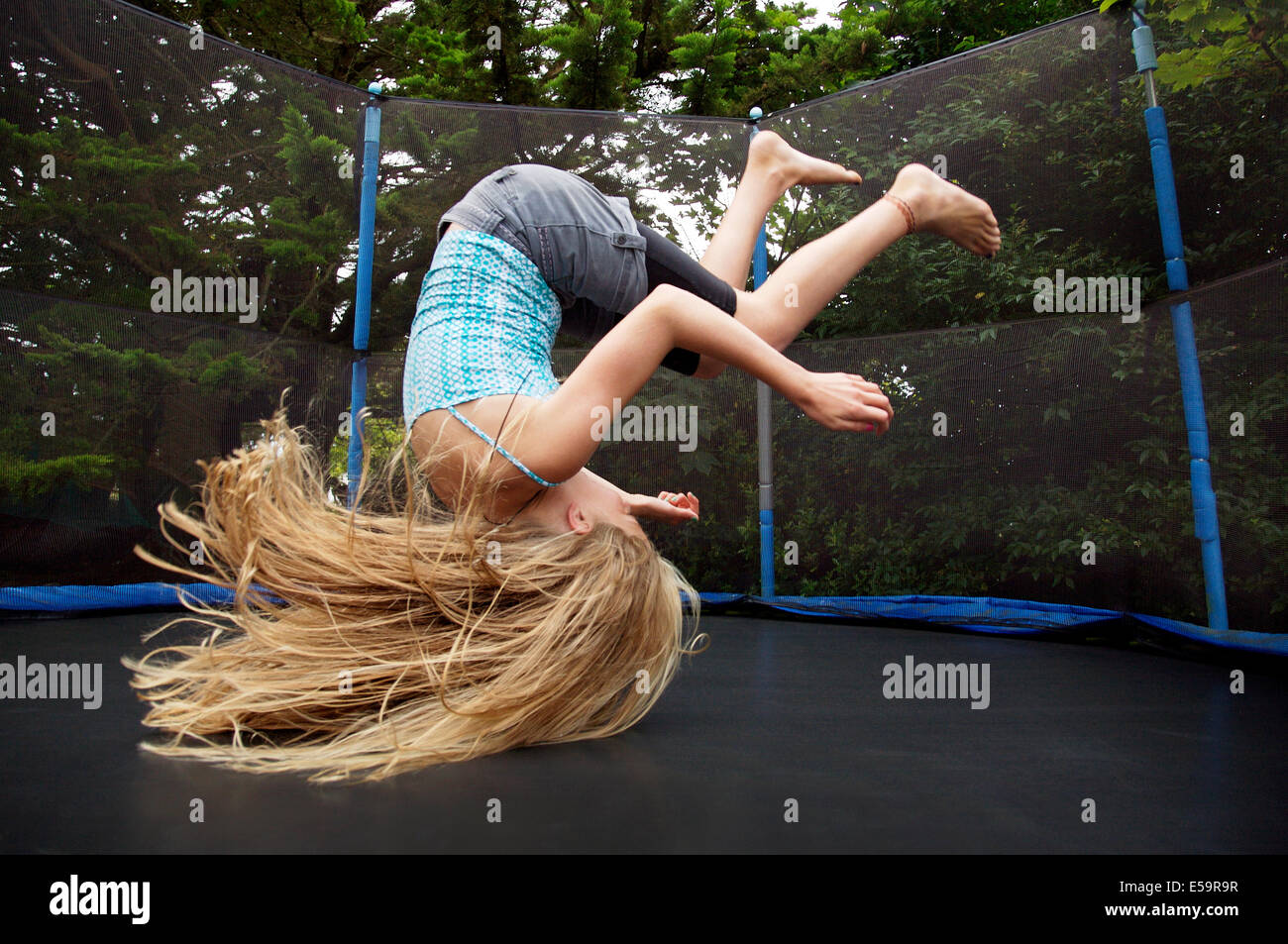 Girl jumping on trampoline outdoors Stock Photo