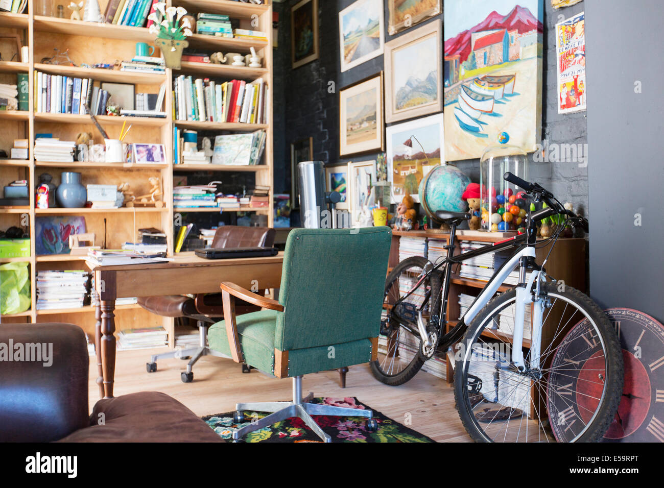 Desk, bookshelves and bicycle in study Stock Photo