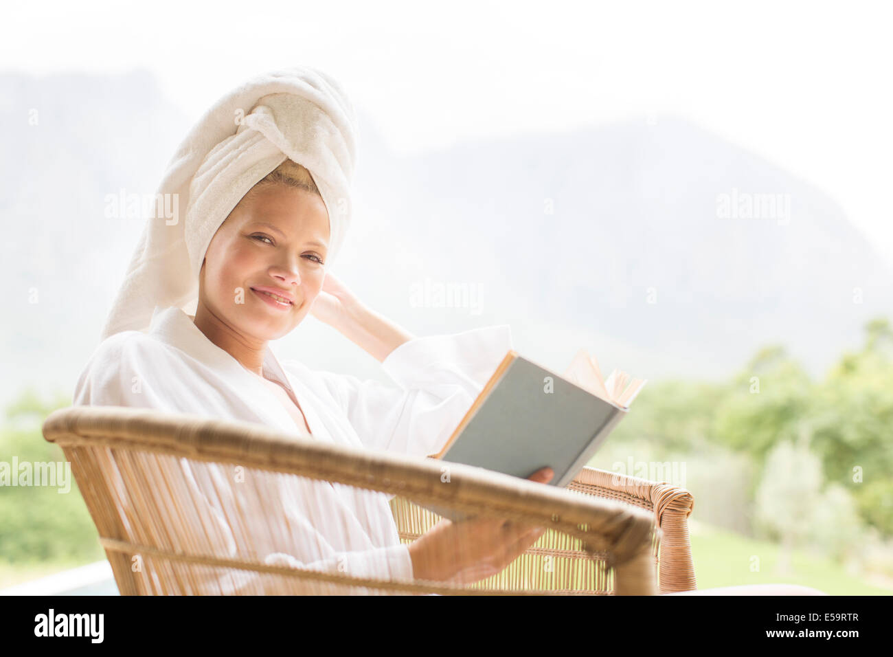 Woman in bathrobe reading outdoors Stock Photo
