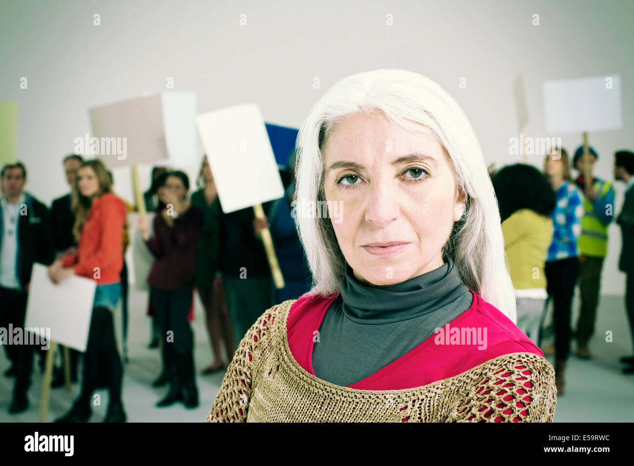 Portrait of serious woman with protesters in background Stock Photo