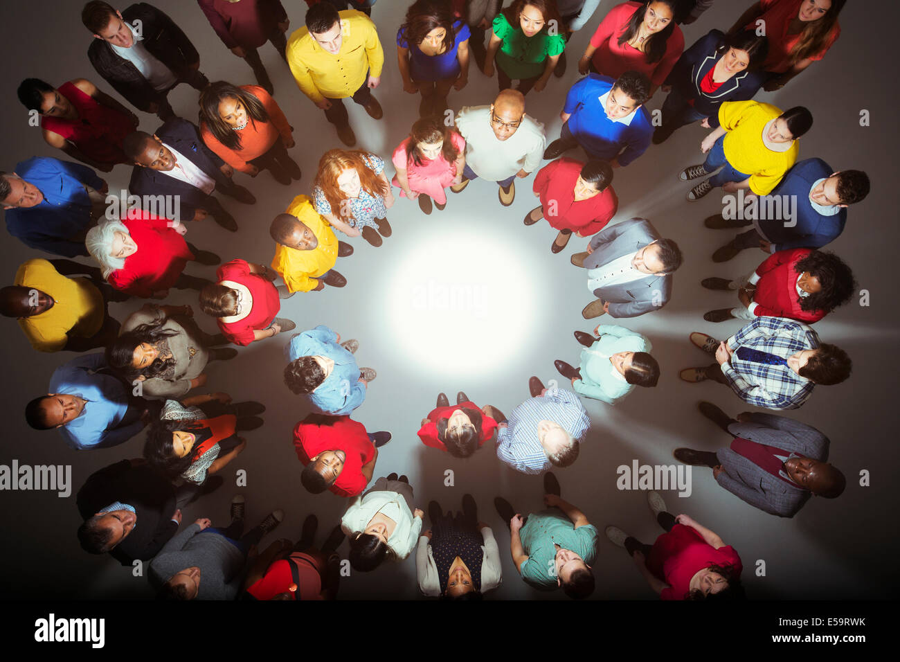 Diverse crowd standing around bright light Stock Photo