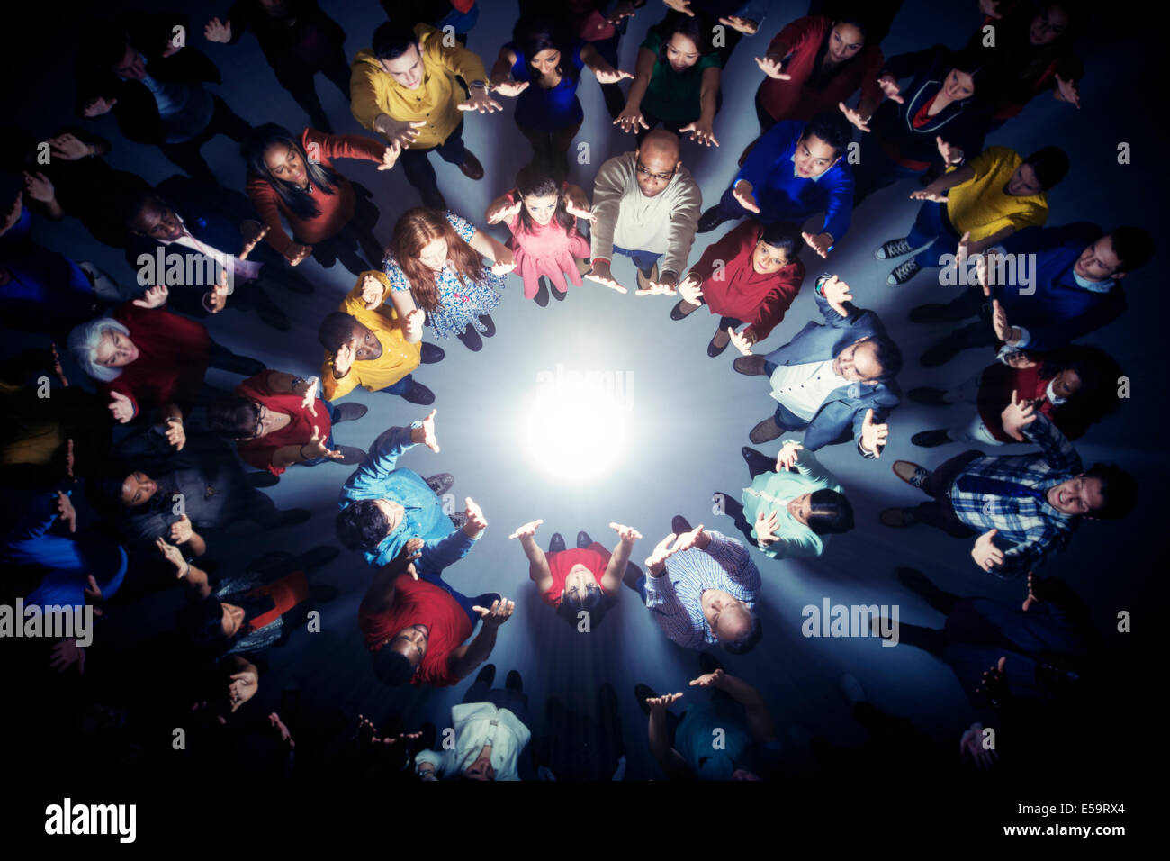 Business people forming circle around bright light Stock Photo