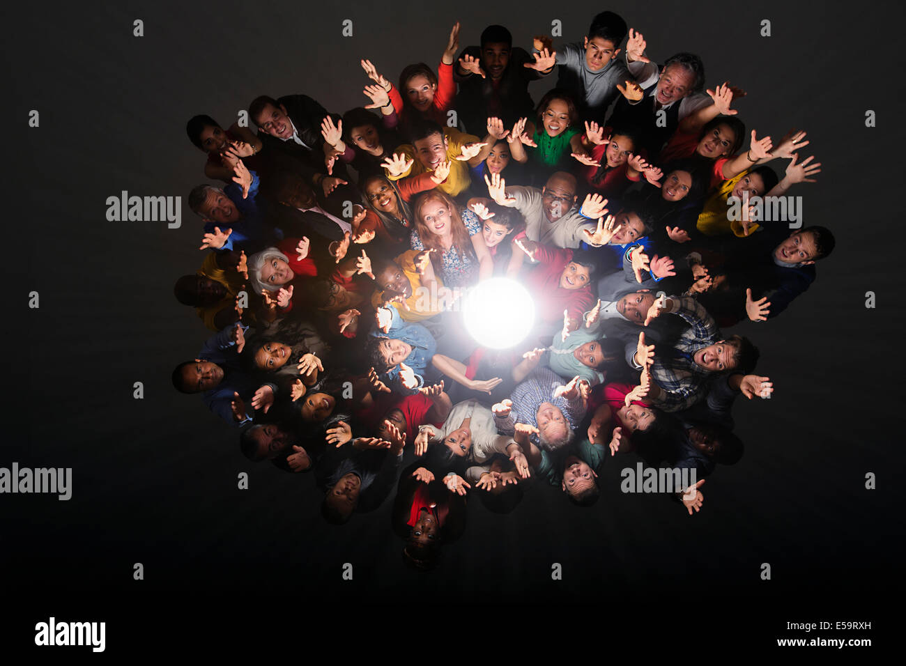 Diverse crowd cheering around bright light Stock Photo