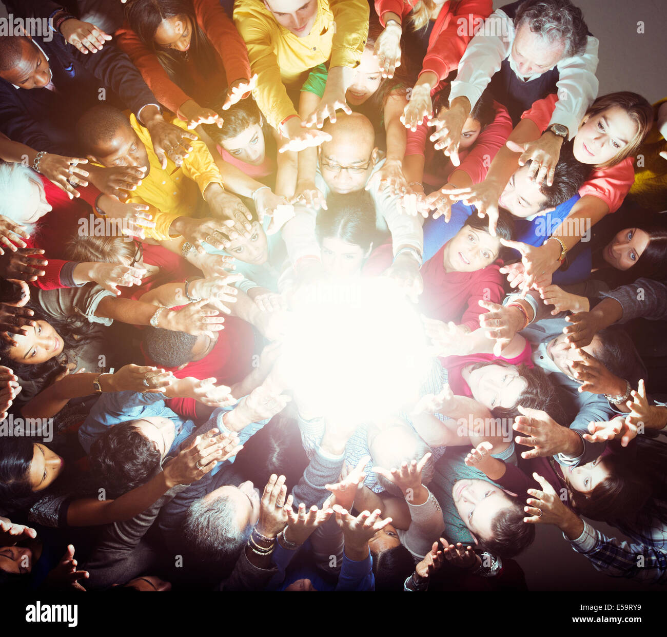 Diverse crowd reaching for bright light Stock Photo