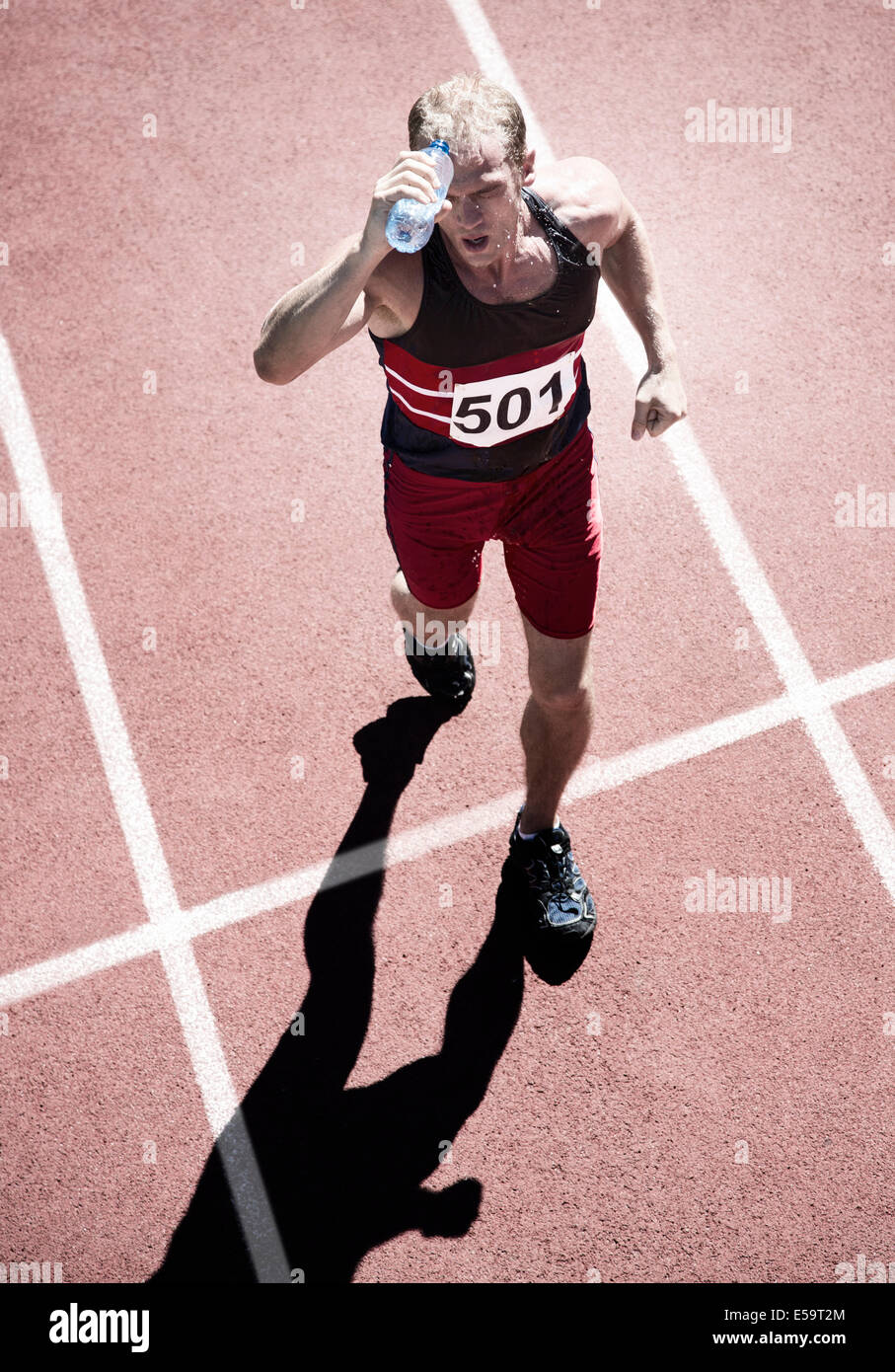 Runner pouring water overhead on track Stock Photo