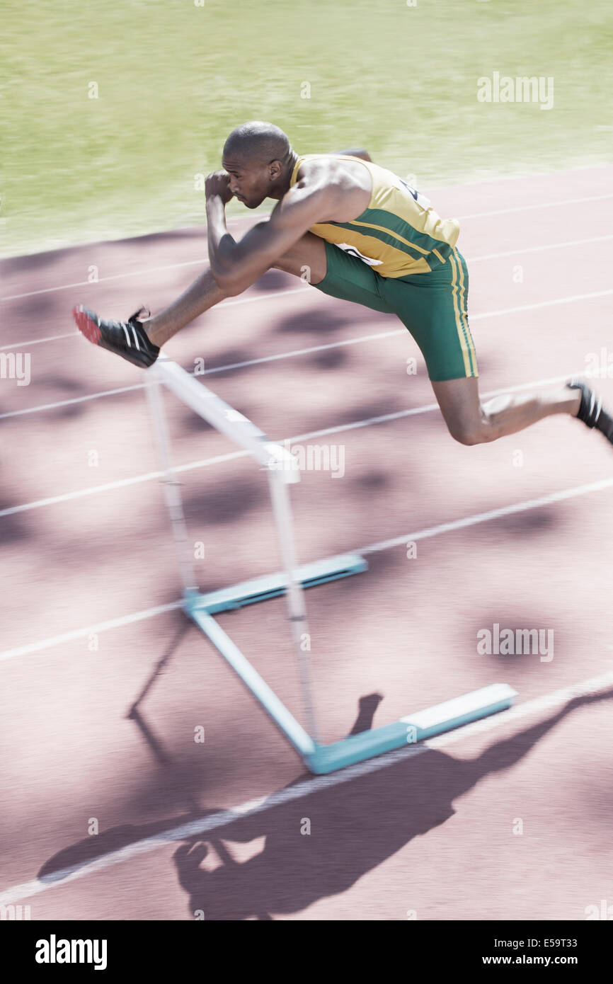 Runner clearing hurdle on track Stock Photo Alamy