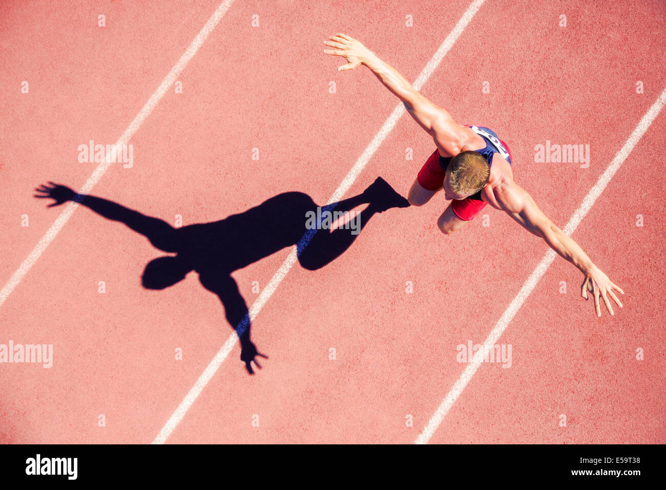 Track and field athlete jumping on track with arms outstretched Stock