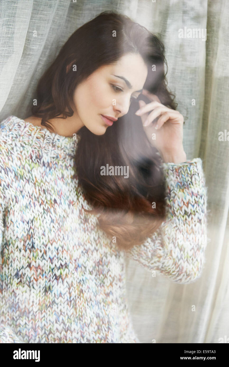 Woman standing by window Stock Photo