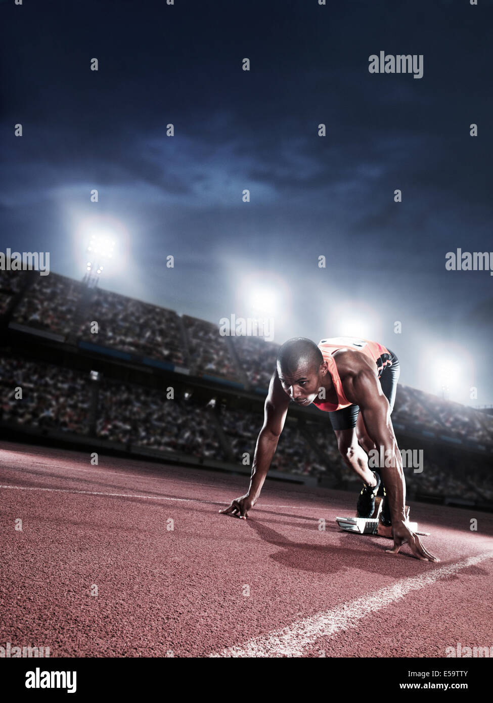 Runner poised at starting line on track Stock Photo