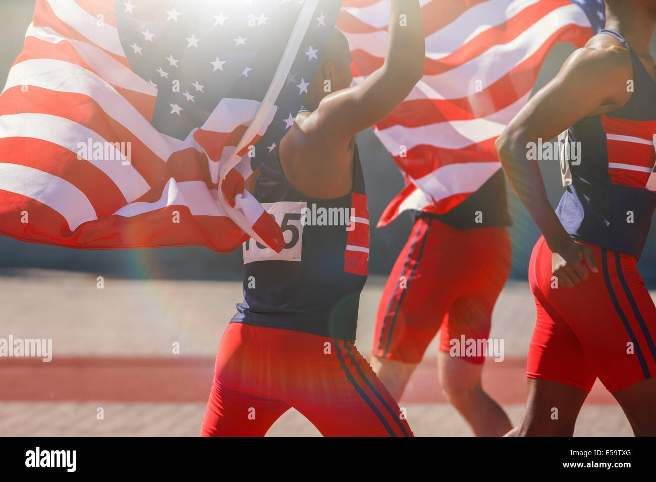 Track and field athletes holding American flags on track Stock Photo