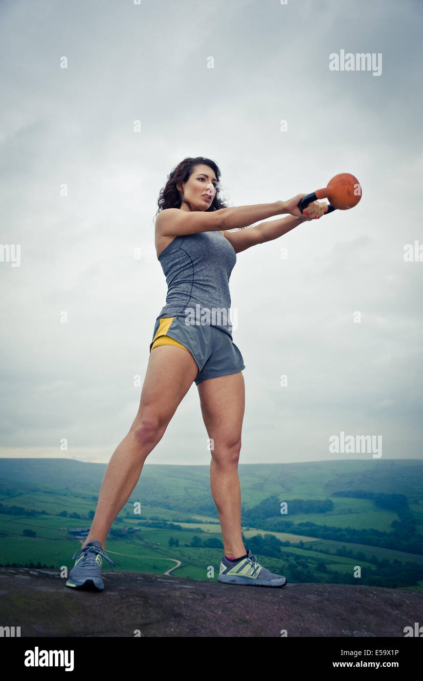 Woman exercising outdoors using a kettlebell, UK Stock Photo