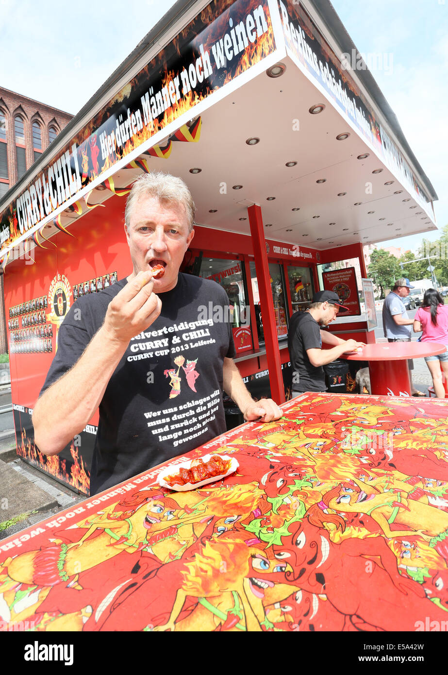 Berlin, Germany. 07th July, 2014. Frank Spiess, owner of the diner 'Curry & Chily', eats a currywurst at his diner in Wedding in Berlin, Germany, 07 July 2014. The diner offers curry sausages in varying degrees of spiciness. Customers who eat a meal with the spiciness degree ten can become a member in the curry club and have their portrait shown at the diner. Photo: Stephanie Pilick/dpa/Alamy Live News Stock Photo
