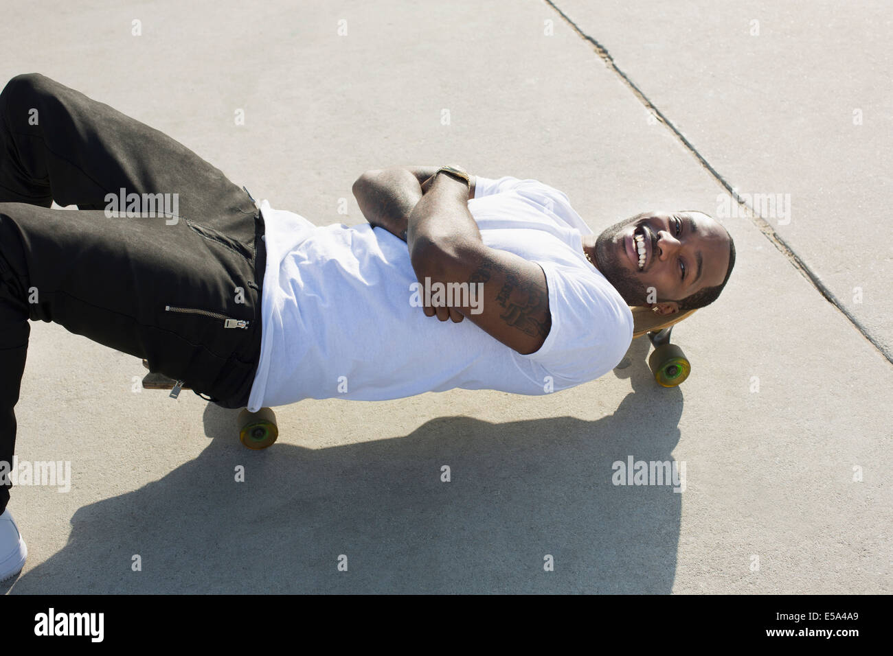 African American man laying on skateboard on city street Stock Photo