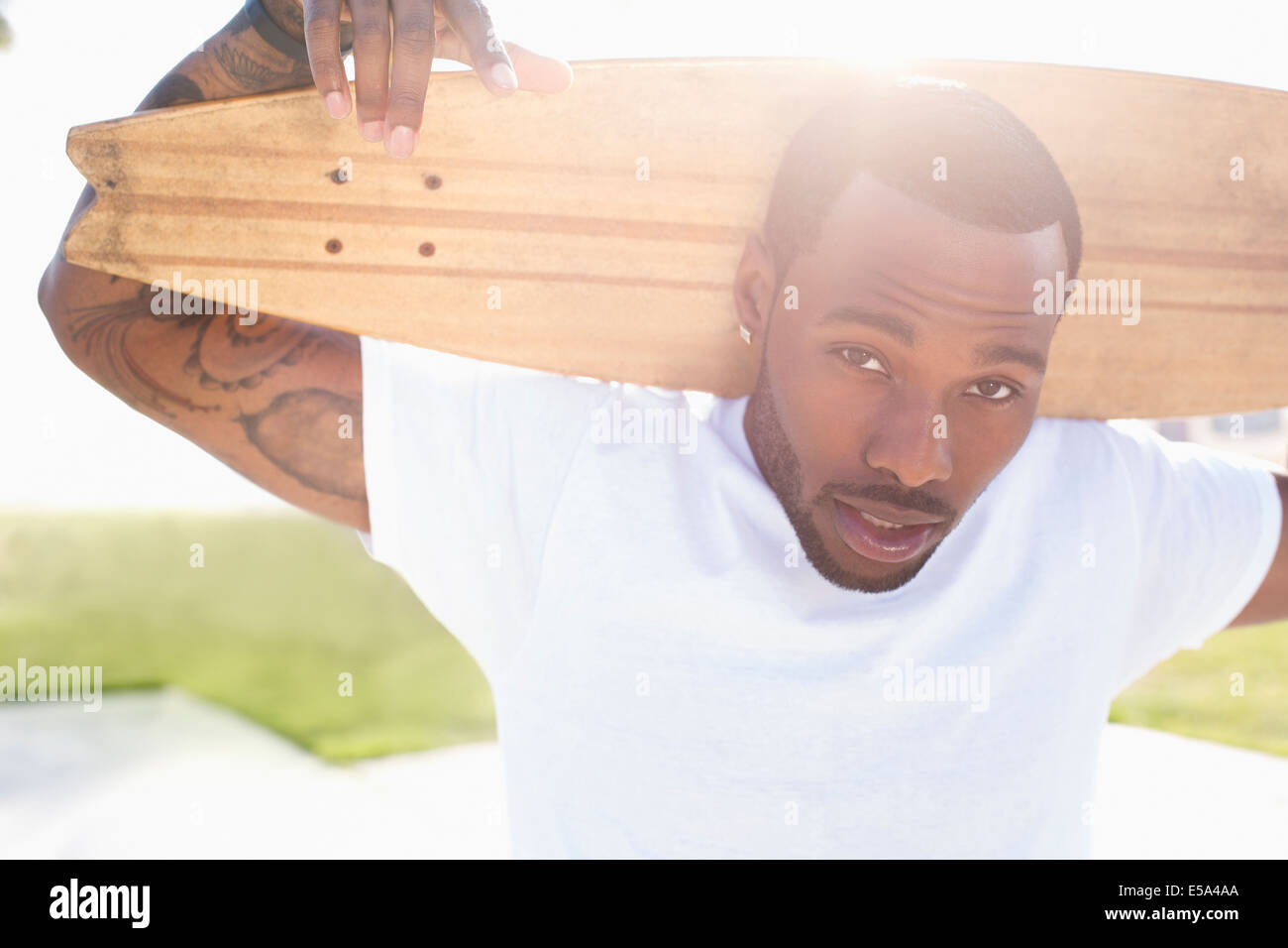 African American man carrying skateboard outdoors Stock Photo