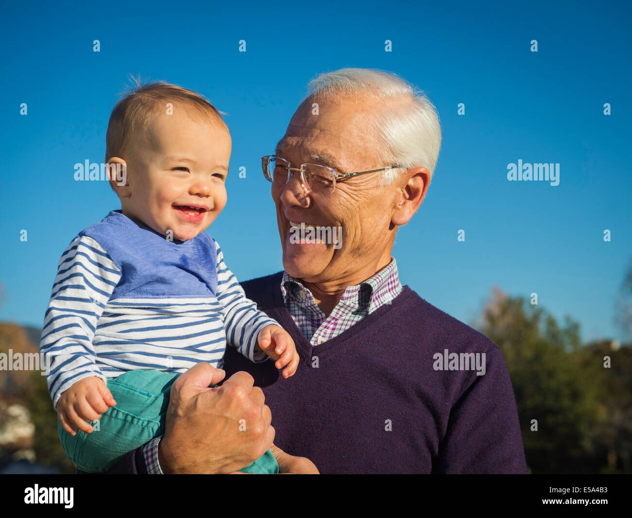 Older man holding grandson outdoors Stock Photo