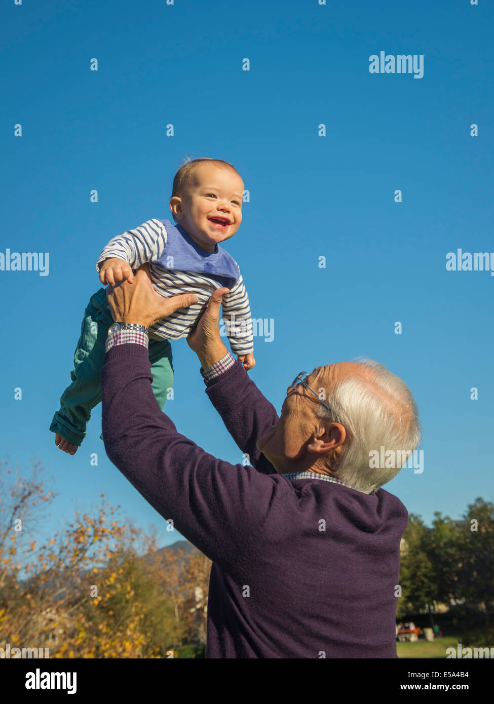 Older man playing with grandson outdoors Stock Photo