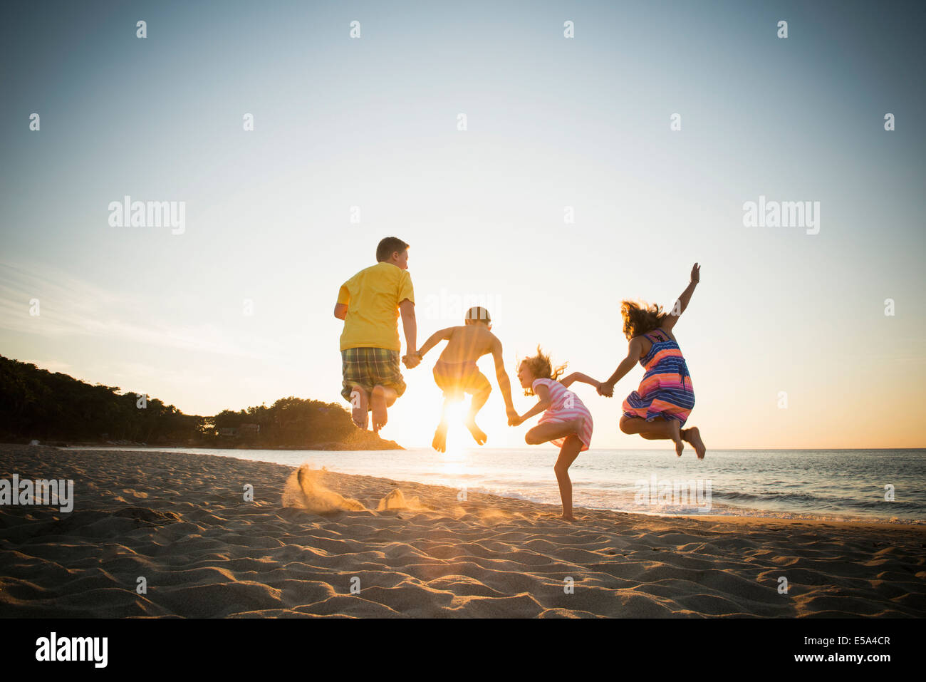 Family jumping for joy on beach Stock Photo