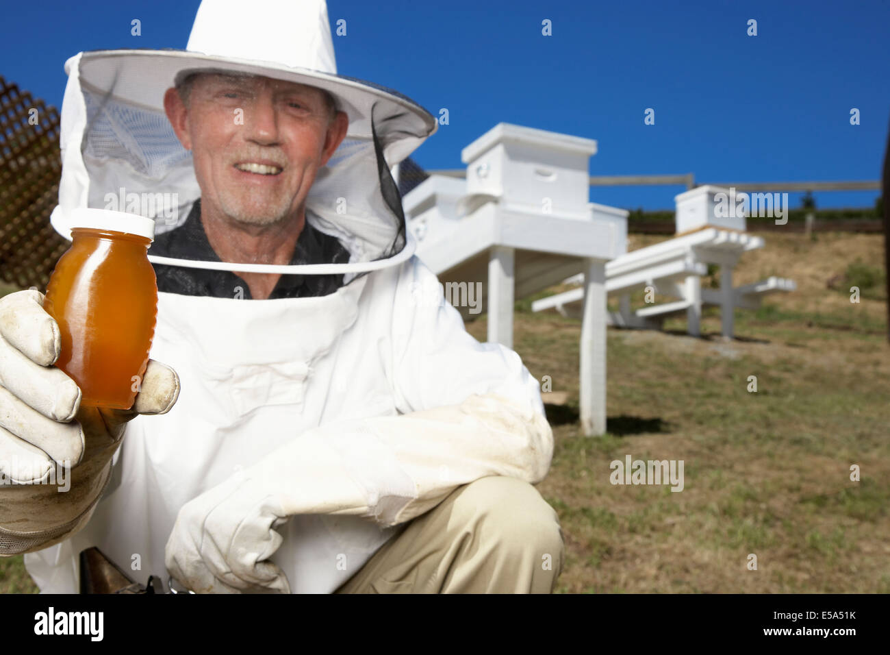 Caucasian beekeeper holding jar of honey Stock Photo