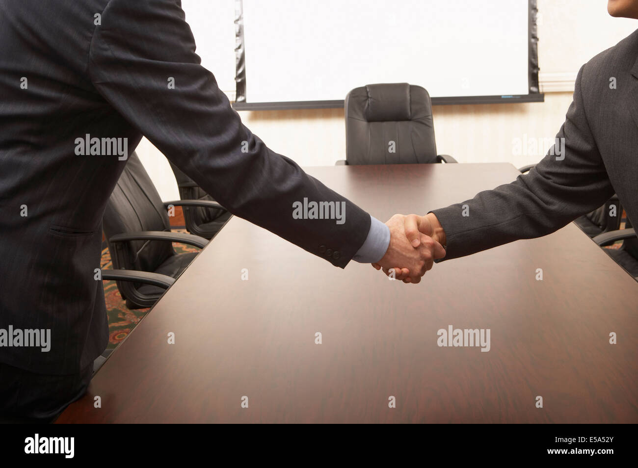 Businessmen shaking hands over conference table Stock Photo