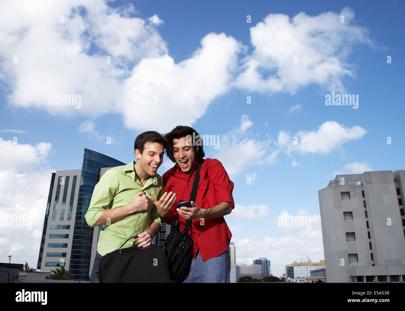 Hispanic men using cell phone on city street Stock Photo